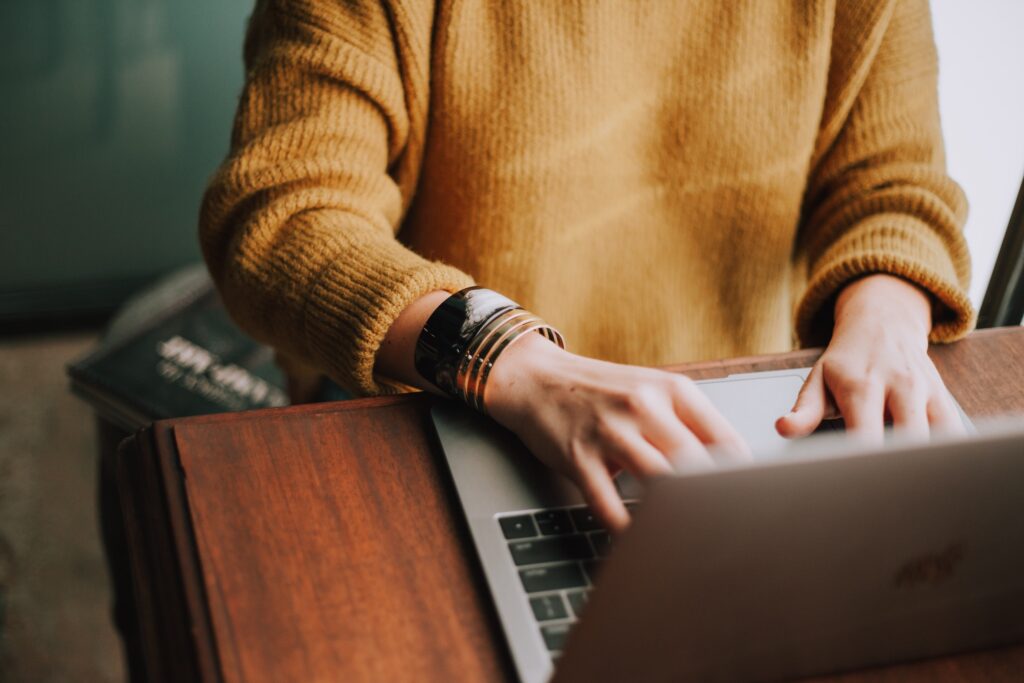 woman's hands tying on laptop