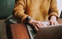 woman's hands tying on laptop